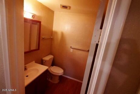bathroom with toilet, wood finished floors, visible vents, baseboards, and vanity