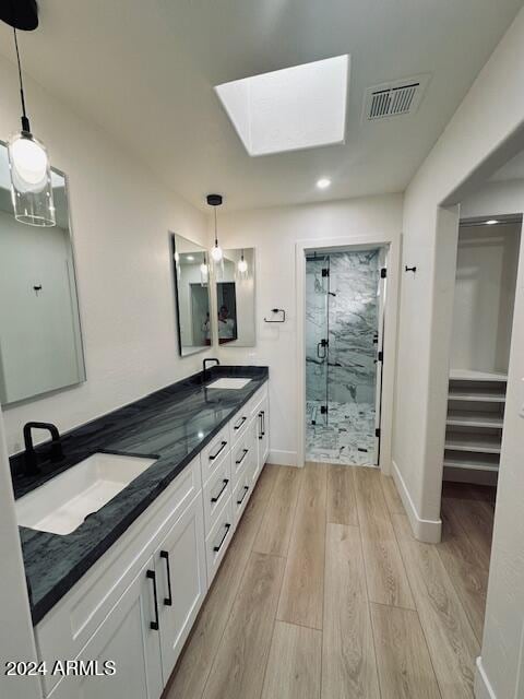 bathroom featuring vanity, an enclosed shower, wood-type flooring, and a skylight