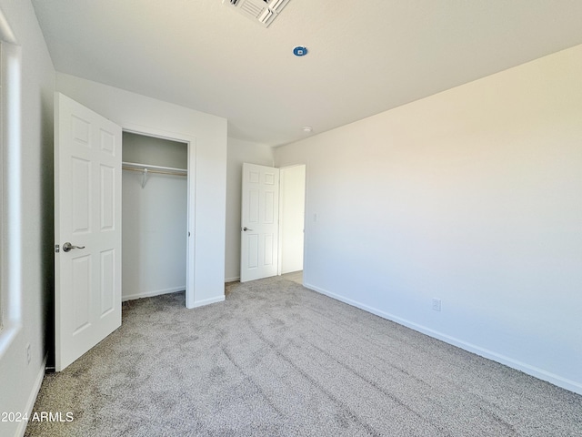 unfurnished bedroom with light carpet and a closet