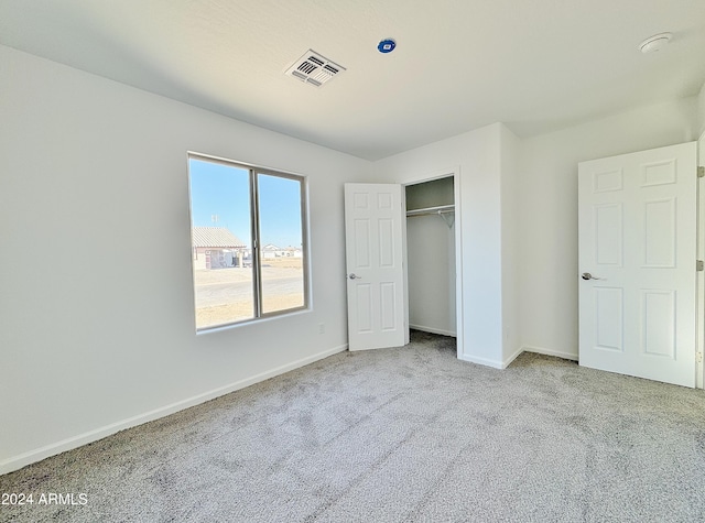 unfurnished bedroom with a closet and light colored carpet