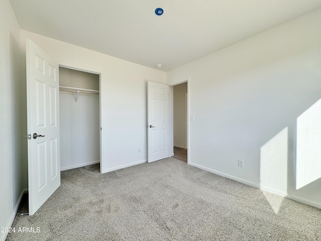 unfurnished bedroom with light colored carpet and a closet