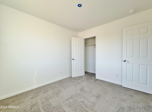 unfurnished bedroom featuring light carpet and a closet