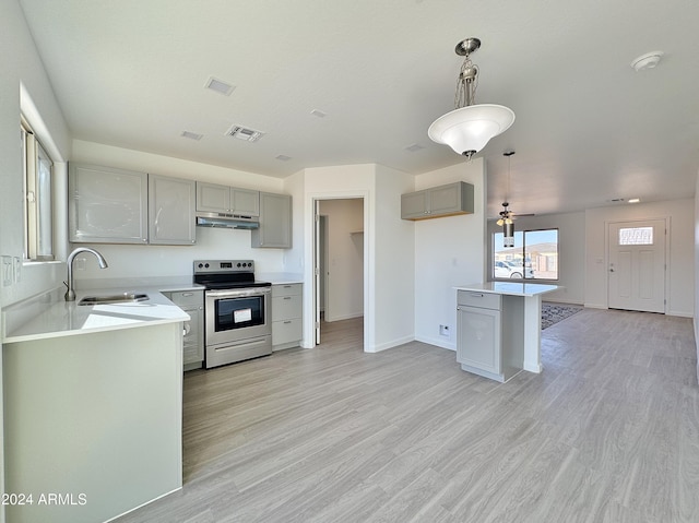 kitchen with electric range, sink, light hardwood / wood-style floors, and decorative light fixtures