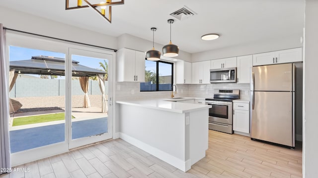 kitchen with tasteful backsplash, visible vents, white cabinets, appliances with stainless steel finishes, and a peninsula