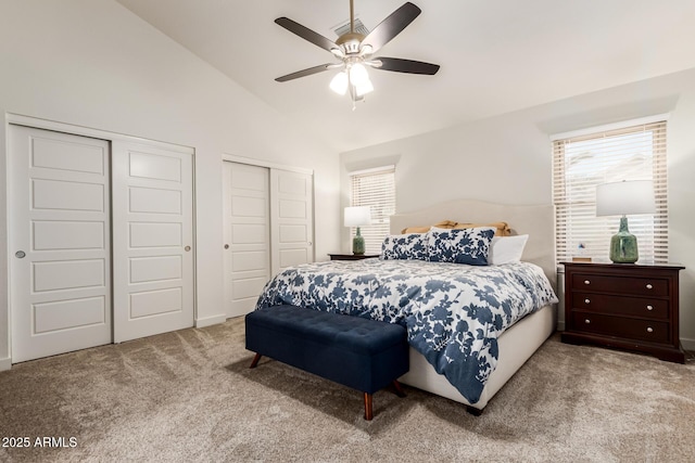 carpeted bedroom with high vaulted ceiling, ceiling fan, and multiple closets