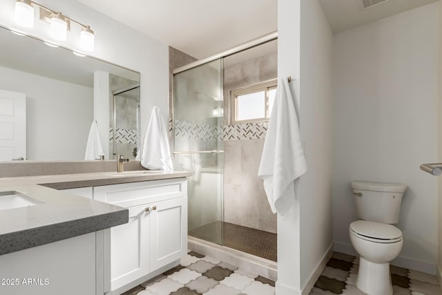 bathroom featuring vanity, toilet, and a shower with shower door