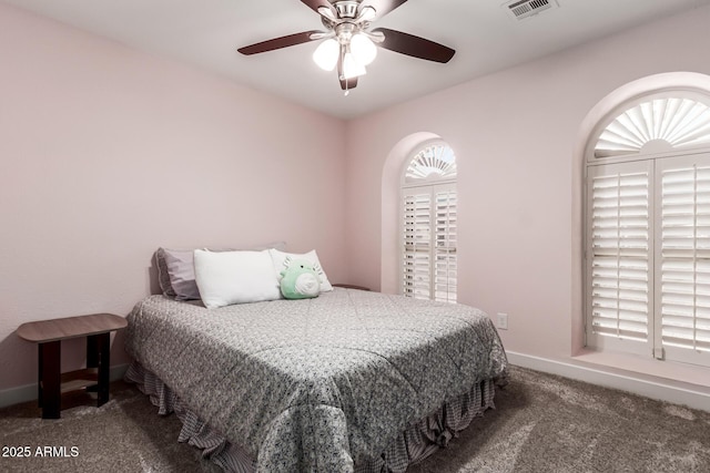 bedroom with multiple windows, ceiling fan, and dark carpet