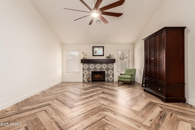 unfurnished living room with a tile fireplace, ceiling fan, light parquet flooring, and vaulted ceiling