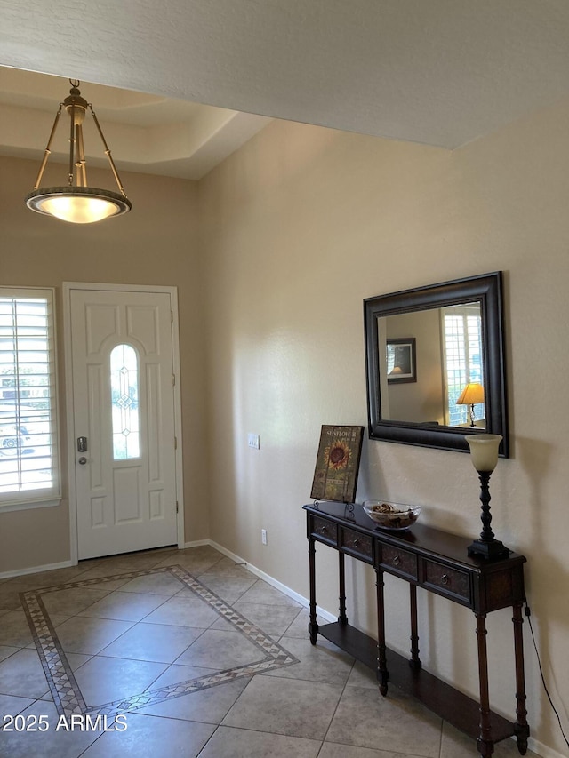 foyer entrance featuring a raised ceiling and light tile patterned floors