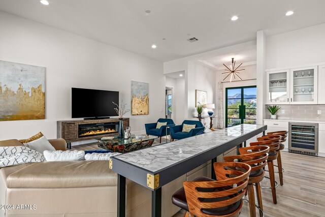 living room featuring beverage cooler, light wood-type flooring, and indoor bar