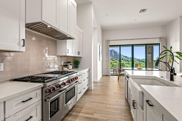 kitchen featuring a mountain view, range with two ovens, light hardwood / wood-style flooring, and white cabinets