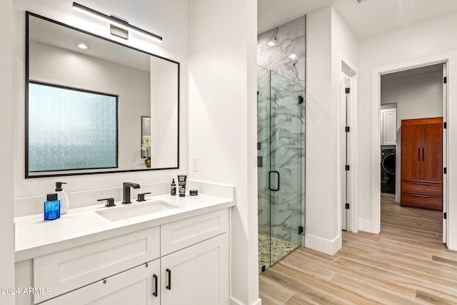 bathroom with washer / clothes dryer, a shower with shower door, vanity, and hardwood / wood-style flooring