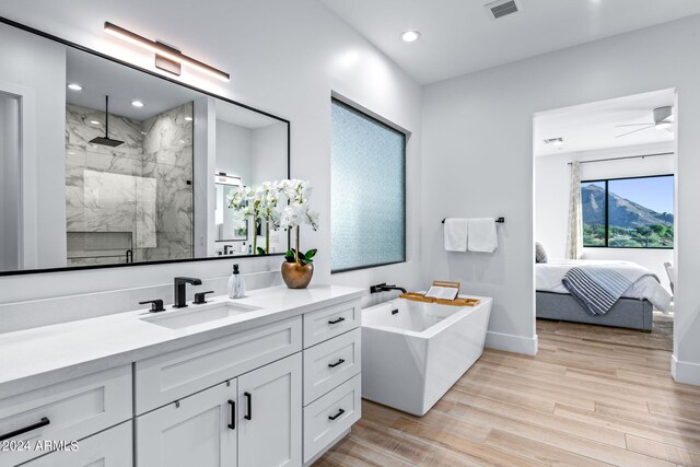 bathroom featuring ceiling fan, vanity, plus walk in shower, and hardwood / wood-style floors