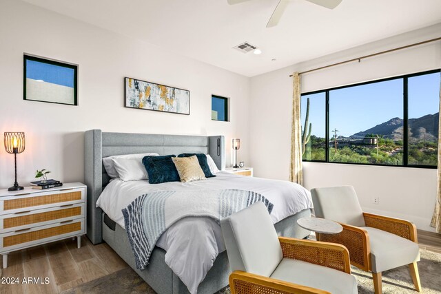 bedroom featuring wood-type flooring, a mountain view, and ceiling fan