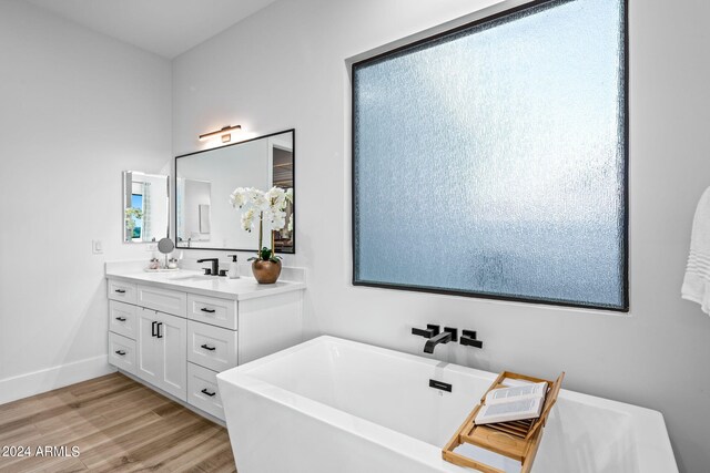 bathroom with wood-type flooring, vanity, and a tub