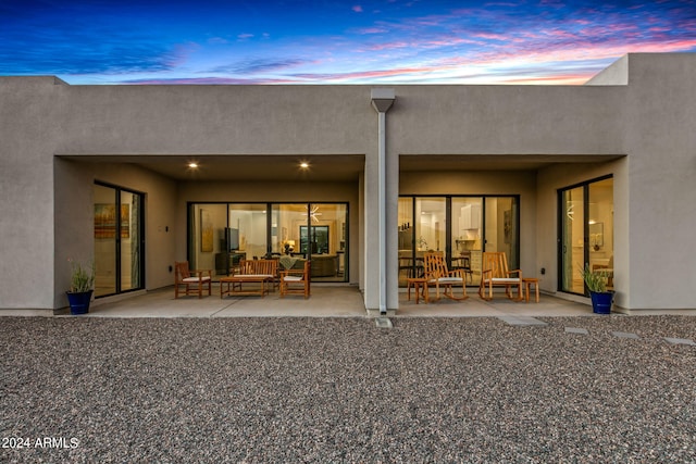 back house at dusk featuring a patio