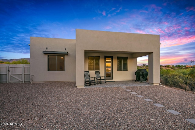 back house at dusk with a patio area