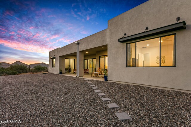 back house at dusk featuring a patio area