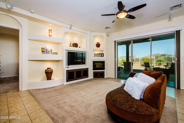 living room featuring ceiling fan, light colored carpet, and built in features