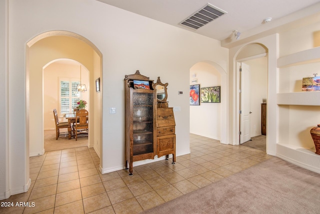 hallway with light colored carpet and built in features