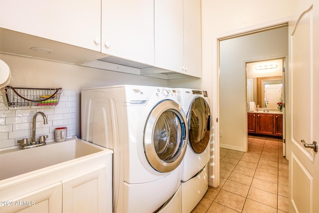 clothes washing area with cabinets, light tile patterned flooring, washer and dryer, and sink