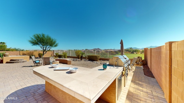 view of patio with area for grilling, a mountain view, and a grill