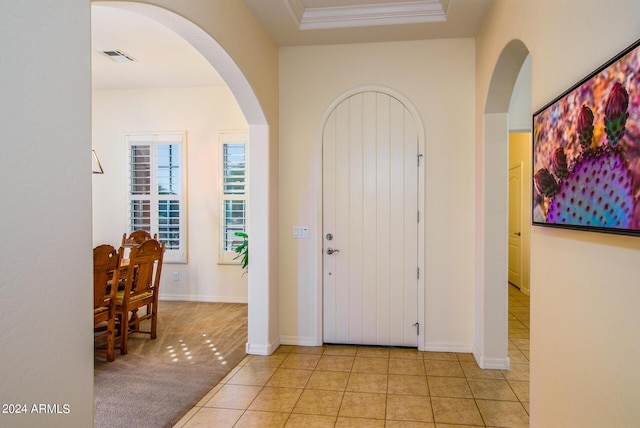 foyer entrance with ornamental molding and light tile patterned floors