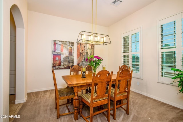 dining area featuring light colored carpet and an inviting chandelier