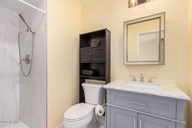 bathroom featuring a tile shower, vanity, and toilet