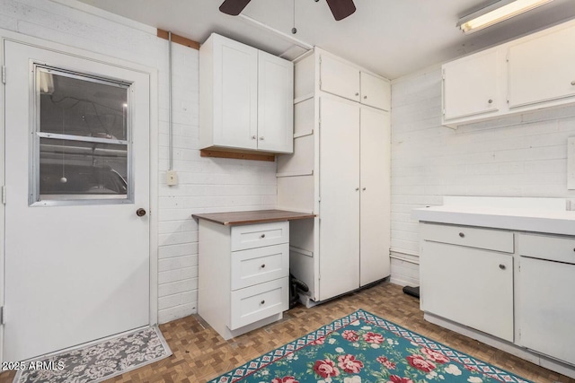 kitchen featuring white cabinetry, ceiling fan, and parquet flooring