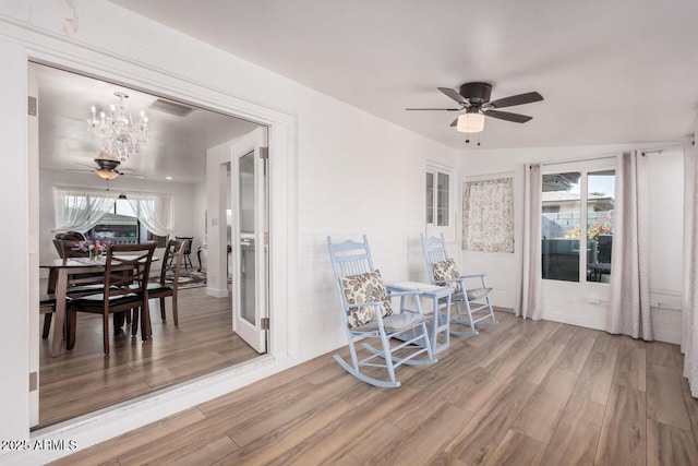 dining space with hardwood / wood-style flooring and ceiling fan with notable chandelier