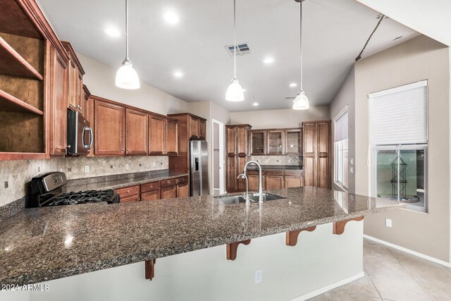 kitchen featuring a kitchen breakfast bar, hanging light fixtures, stainless steel appliances, sink, and decorative backsplash