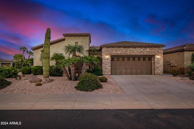 view of front facade featuring stone siding, stucco siding, driveway, and a garage