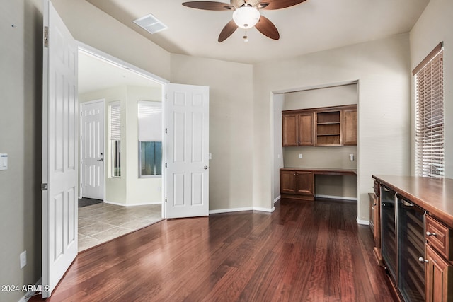 interior space with built in desk, ceiling fan, wine cooler, and dark hardwood / wood-style flooring