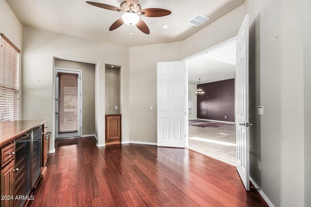 interior space featuring ceiling fan with notable chandelier, wine cooler, and dark hardwood / wood-style floors