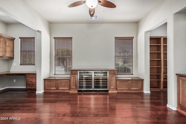 unfurnished living room with built in desk, ceiling fan, beverage cooler, and dark hardwood / wood-style flooring