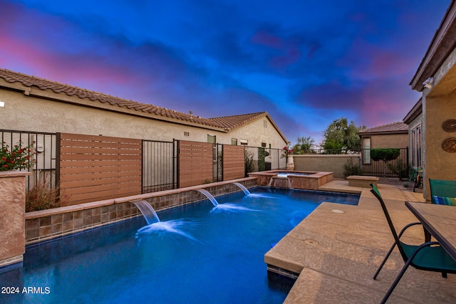 pool at dusk with a patio area, an in ground hot tub, and pool water feature