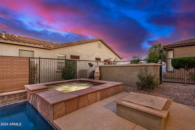 pool at dusk with an in ground hot tub