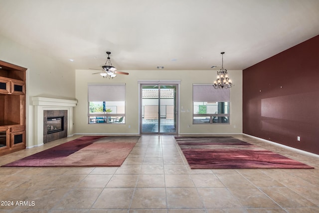 interior space featuring light tile patterned floors, a tiled fireplace, and ceiling fan with notable chandelier