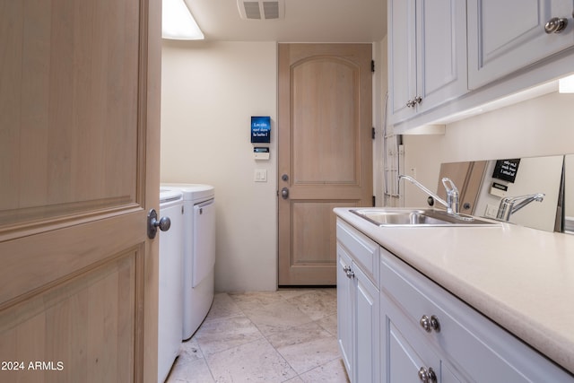 laundry room with washing machine and dryer, cabinets, and sink