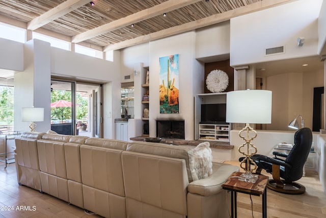 living room featuring wooden ceiling, beam ceiling, a high ceiling, and light wood-type flooring