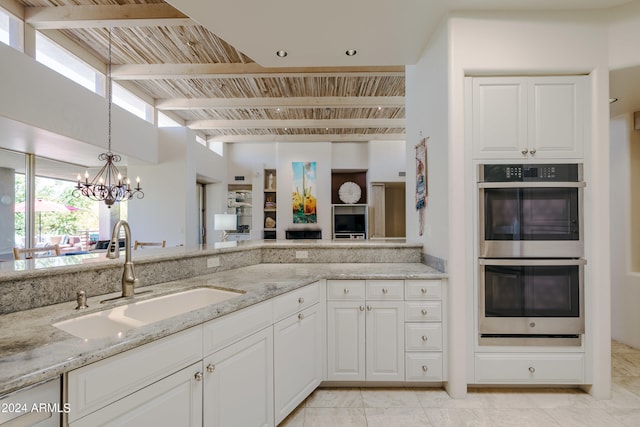 kitchen featuring light stone countertops, double oven, white cabinets, and sink