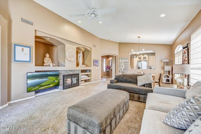 carpeted living room featuring ceiling fan with notable chandelier and vaulted ceiling