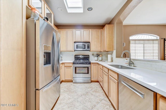 kitchen featuring appliances with stainless steel finishes, sink, light brown cabinets, and decorative backsplash