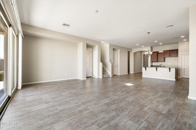 20473 W Legend Trl, Buckeye, AZ 85396 - unfurnished living room with a chandelier, recessed lighting, stairs, light wood-style floors, and baseboards
