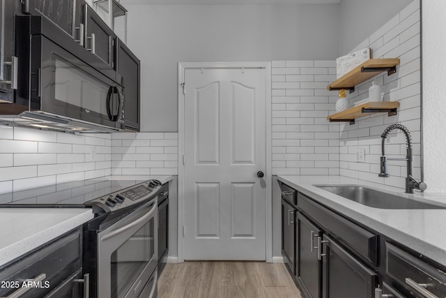 kitchen with light stone countertops, decorative backsplash, light wood-type flooring, sink, and stainless steel range with electric cooktop