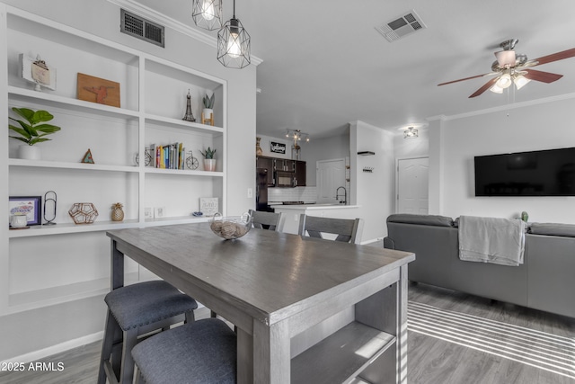 dining room featuring built in shelves, ceiling fan, sink, and hardwood / wood-style flooring