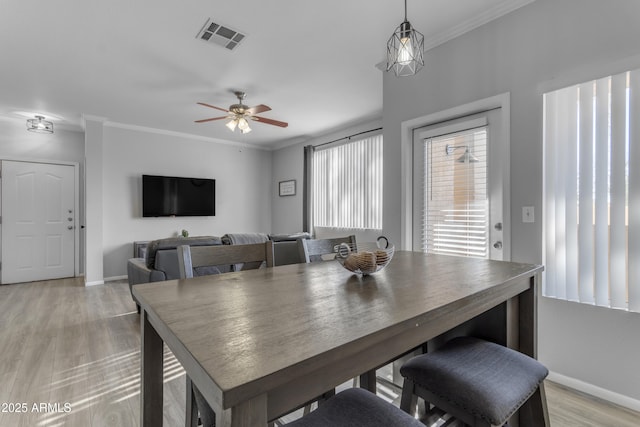 dining space featuring ceiling fan, light wood-type flooring, and crown molding