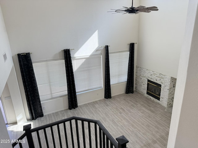 living area featuring light wood-style flooring, visible vents, a ceiling fan, and a glass covered fireplace