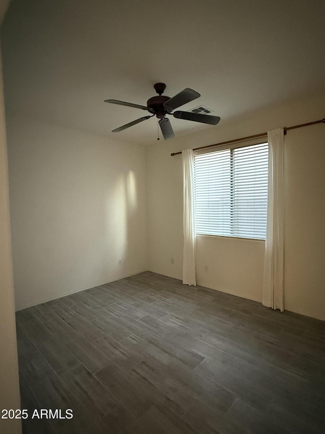 empty room featuring dark wood-style floors, visible vents, and ceiling fan